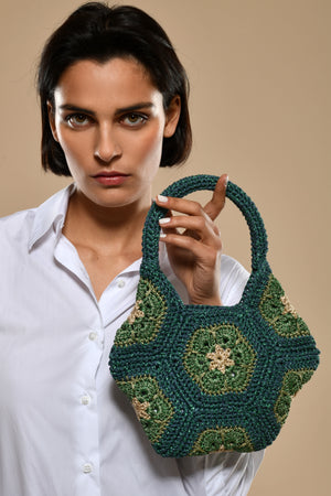 Woman holding a green crocheted hexagonal handbag, Made in Italy.
