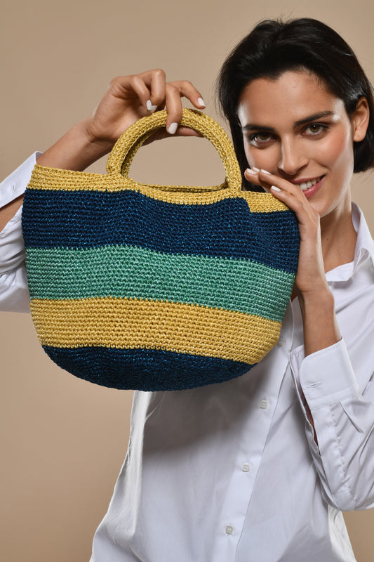 Woman holding a hand crochet handbag against a beige background