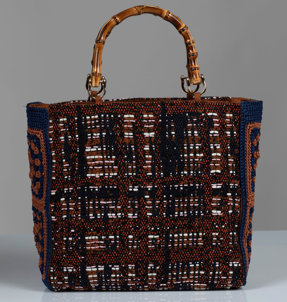 Woven handbag with a patterned design with bamboo handles.  