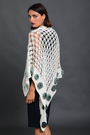 Woman wearing a white hand crochet shawl  trimmed with sage green roses. 