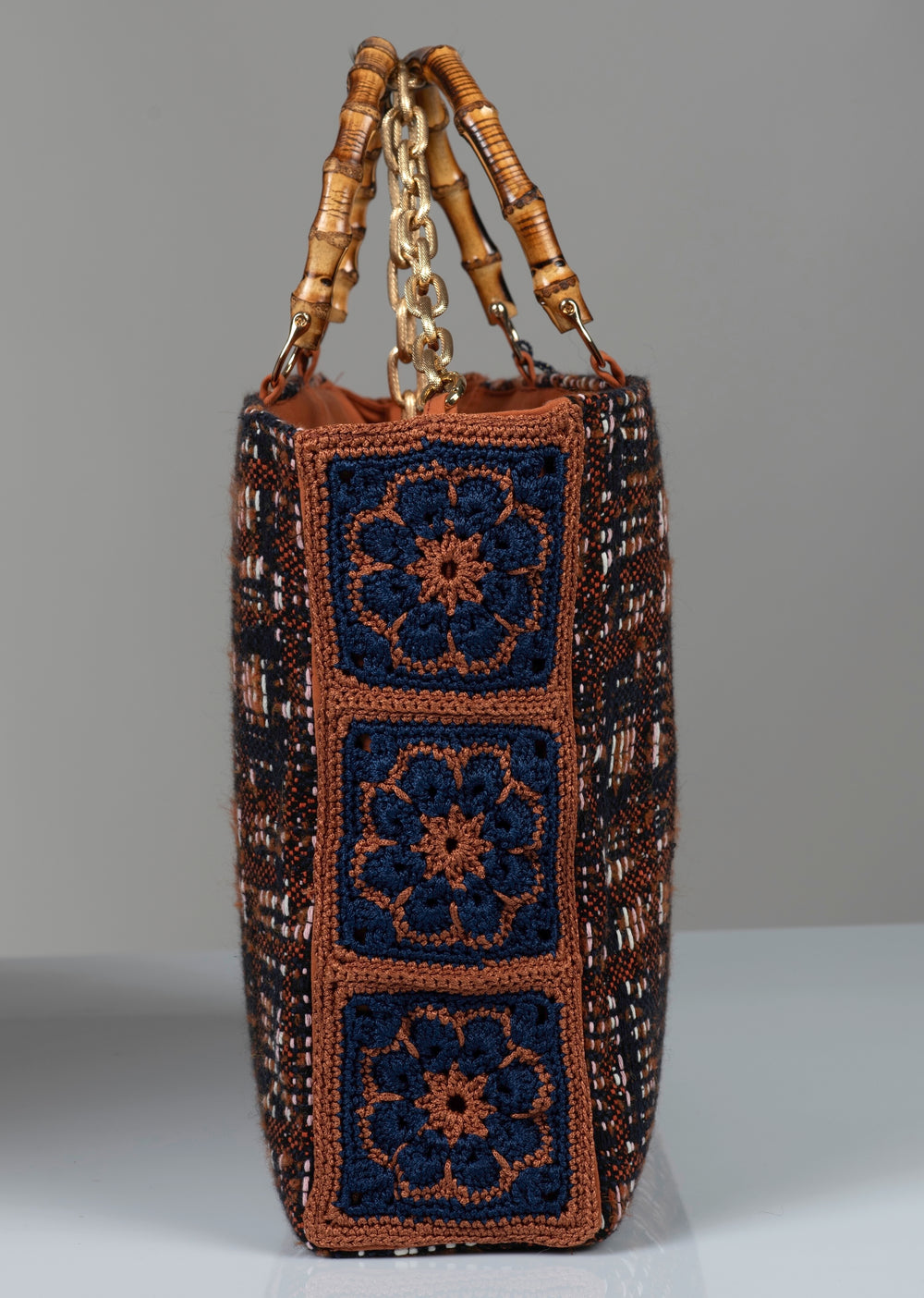 Cotton wool textured handbag with crochet floral patterns and gold chain handle.